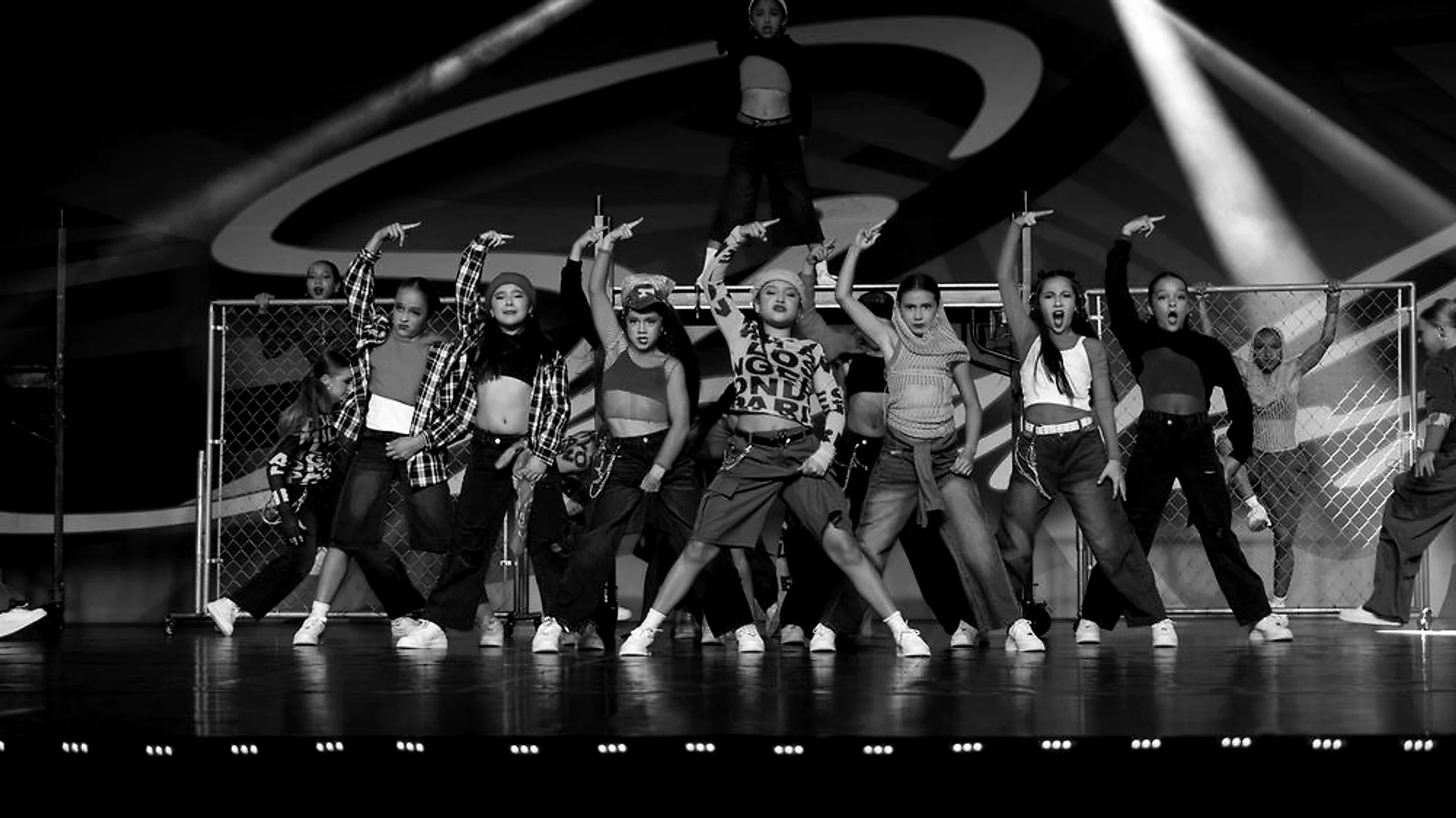 Dancing Images hip hop dancers mid-performance on stage under coloured lights