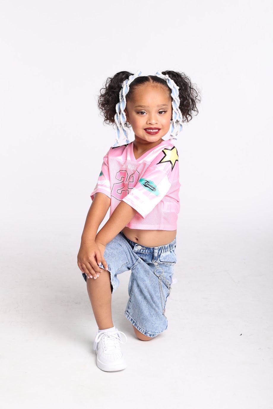 Young DIDC hip hop dancer in a pink jersey, kneeling mid-pose